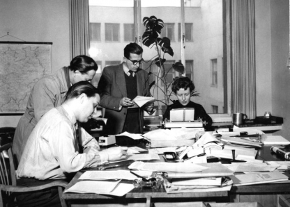 Archieffoto van mannen en vrouwen die aan een bureau werken