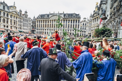 Mannen in traditionele kledij dragen een meiboom op de Grote Markt van Brussel