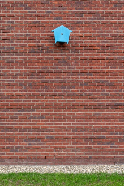 bakstenen muur met blauw tweedimensionaal vogelhuisje