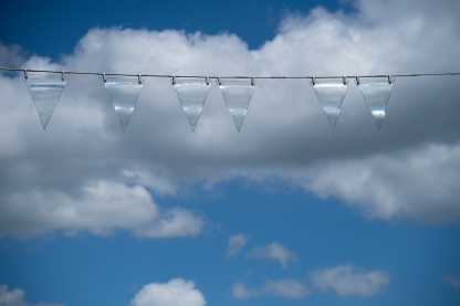 vlaggenlijn met doorzichtige glazen vlagjes voor blauwe lucht met witte wolken