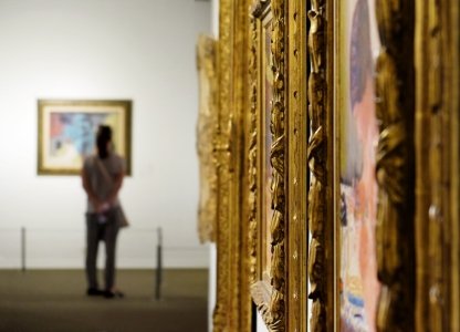 schilderijkaders met op achtergrond een persoon die naar een schilderij kijkt